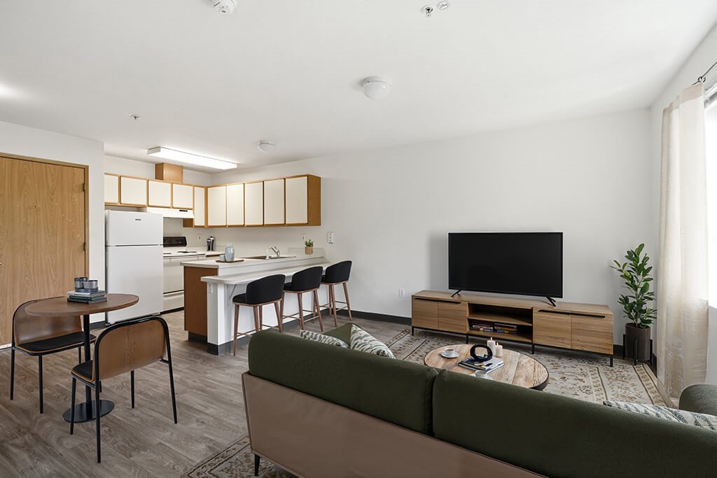 A modern living room with a green sofa, a wooden coffee table, and a television.